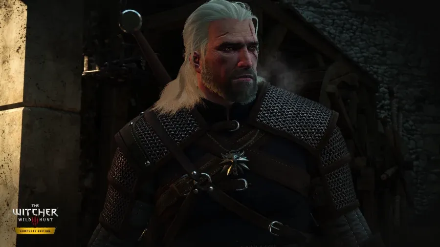 Avant : Geralt en gros plan devant une forge dans The Witcher 3 Complete Edition, avec un éclairage plus terne et des détails plus doux sur l’armure et la barbe.