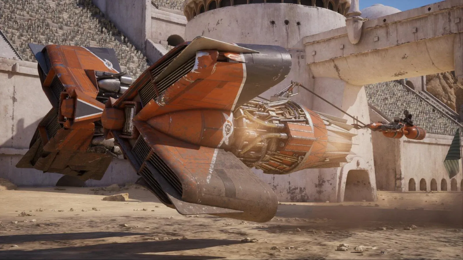 Un podracer orange et rouillé file dans une arène de pierre claire, devant des gradins remplis de spectateurs.