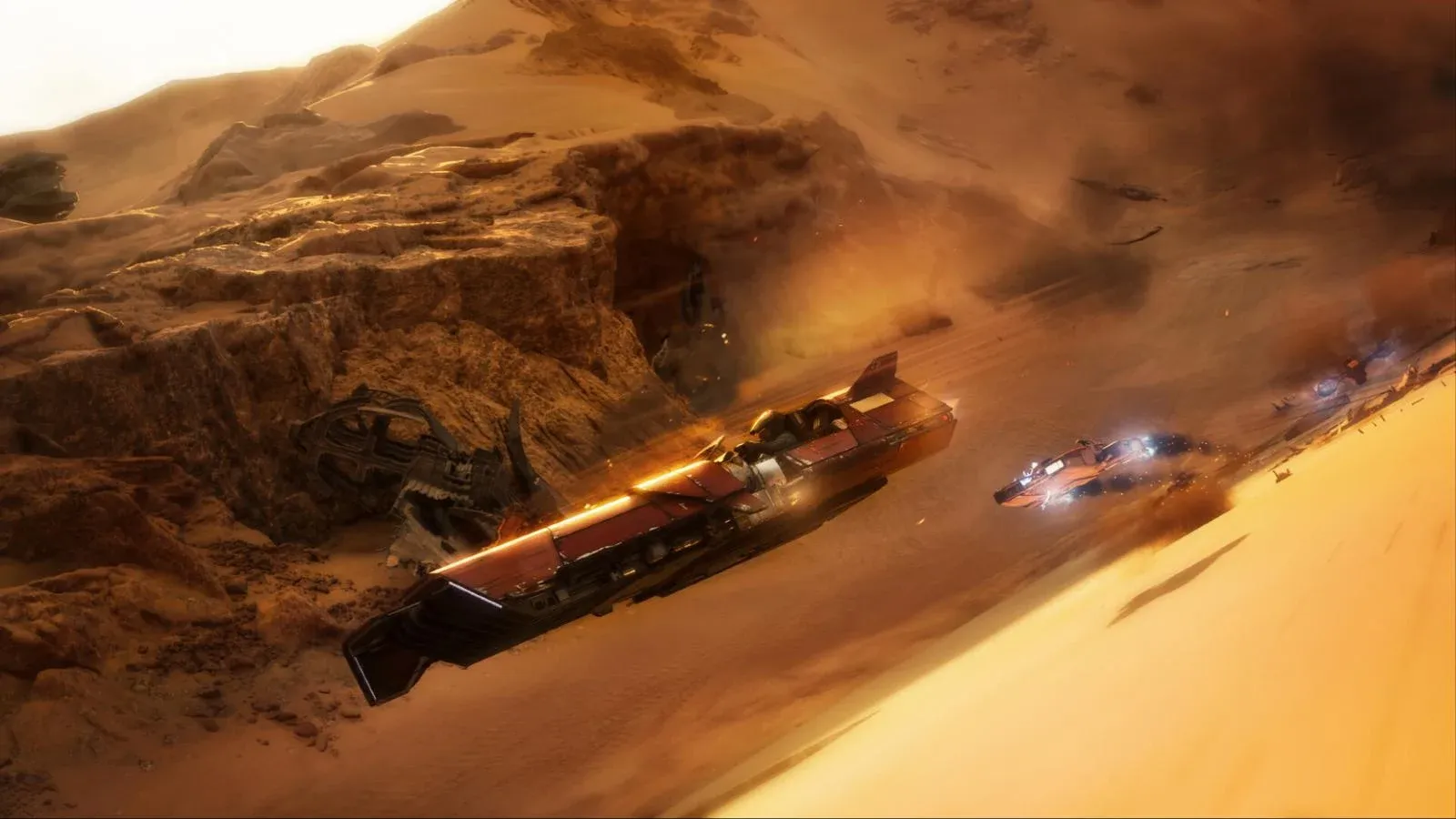Des véhicules de course lancés à pleine vitesse sur une dune du désert, dans un nuage de sable et de poussière.