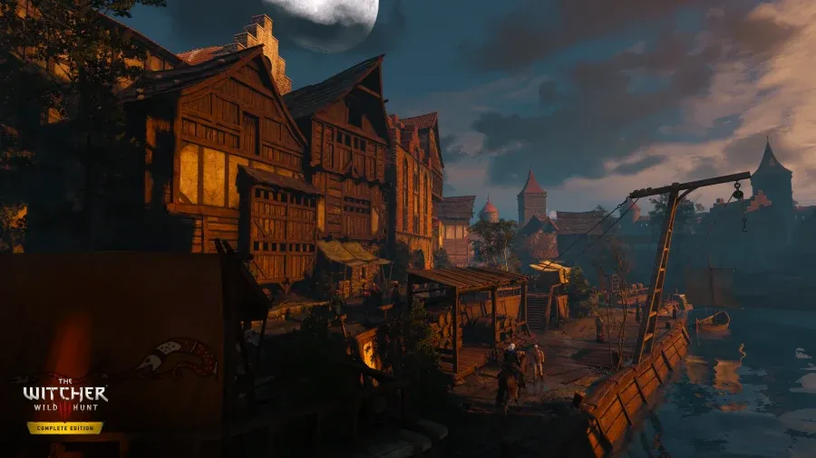 Avant : Geralt sur Ablette longe les quais d’une ville au crépuscule dans The Witcher 3 Complete Edition, avec des façades à colombages dans l’ombre sous un ciel sombre.